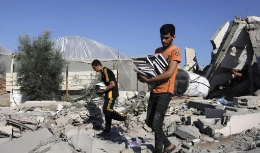 غزيون يحملون كتبا وسط الأنقاض | المصدر: وفا