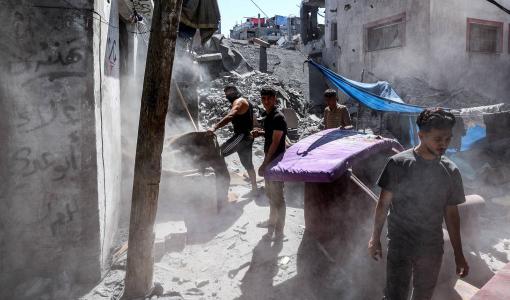 غزيون يتفقدون أنقاض مبنى دمره قصف إسرائيليٍ على مخيم البريج للاجئين الفلسطينيين وسط قطاع غزة | المصدر: وكالة الأنباء الفرنسية