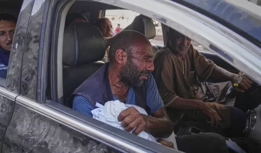 رجل يحمل جثة طفل استشهد في غارة إسرائيلية استهدفت مدرسة في شمال قطاع غزة 27/6/2025 | المصدر: أسوشييتد برس