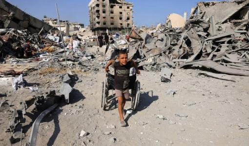 طفل غزي يجر بقايا كرسي متحرك وسط الدمار الذي خلفته غارات الاحتلال على غزة | المصدر: رويترز