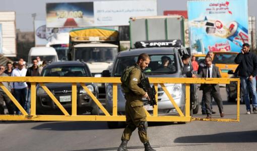 جندي إسرائيلي يقف أمام حاجز عسكري ويمنع مركبات الفلسطينيين من العبور