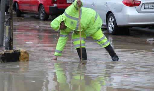 أحد كوادر أمانة عمان يحاول تصريف تجمع للمياه في أحد شوارع العاصمة | بترا
