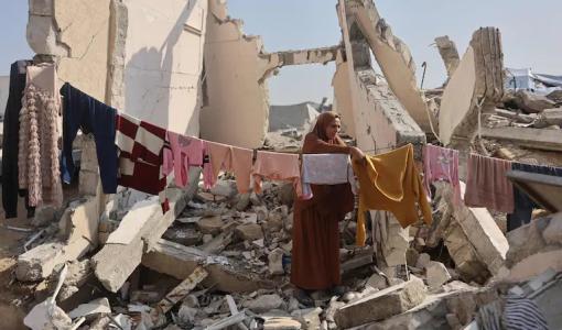 سيدة فلسطينية تقف وسط أنقاض منزل مدمر في غزة تنشر ملابس على حبل غسيل يمتد بين الركام 18/11/2025 | وكالة الأنباء الفرنسية