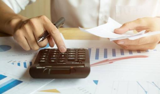 شخص يجري عملية حسابية على آلة حاسبة | تعبيرية