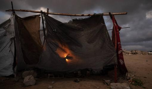 أفراد عائلة فلسطينية نازحة يتجمعون حول نار في خيمتهم في مدينة خانيونس جنوب قطاع غزة | الوكالة الأوروبية للصور الصحفية