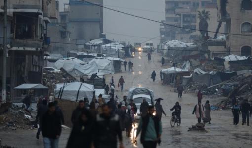 فلسطينيون يسيرون تحت المطر في ظروف إنسانية قاسية تعكس آثار حرب الإبادة الإسرائيلية على غزة