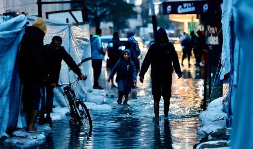 نازحون يمرون عبر برك المياه جراء الأمطار الغزيرة في مدينة غزة 15/12/2025 | وكالة الأنباء الفرنسية