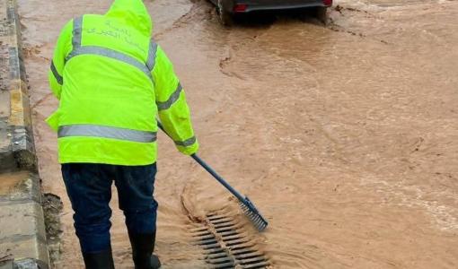 أحد كوادر بلدية مأدبا يعمل على تصريف مياه أمطار غمرت أحد الشوارع إثر هطولات مطرية غزيرة | أرشيفية