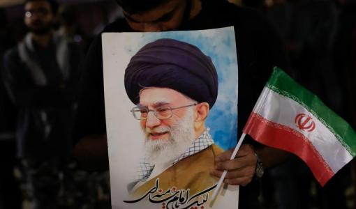 شاب يحمل صورة علي خامنئي والعلم الإيراني | رويترز