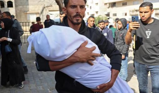 رجل يحمل جثمان طفل استشهد جراء قصف مدفعي إسرائيلي على منازل سكنية قرب مستشفى كمال عدوان في بيت لاهيا شمال قطاع غزة 25/4/2026 | وكالة الأنباء الفرنسية