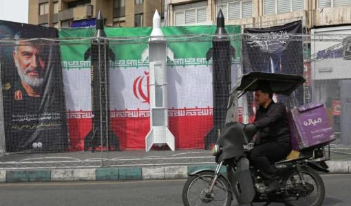 سائق دراجة نارية يمر بمحاذاة نماذج صواريخ إيرانية نصبت على جانب الطريق في طهران | وكالة الأنباء الفرنسية