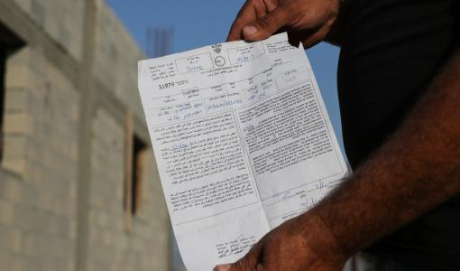 فلسطيني يستعرض إخطارا بهدم منزله تسلمه من قوات الاحتلال في وقت سابق بالضفة الغربية | وفا