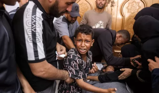 طفل فلسطيني بجوار جثمان شقيقه الذي استشهد بغارة إسرائيلية في خانيونس جنوب غزة 24/6/2026 | وكالة الأنباء الفرنسية