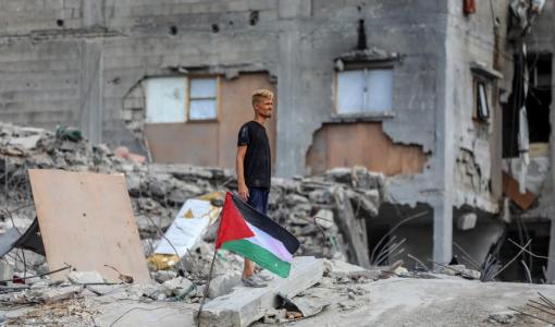شاب بجانبه العلم الفلسطيني فوق أنقاض مبنى مدمر في جباليا شمالي قطاع غزة 24/10/2025 |شينخوا