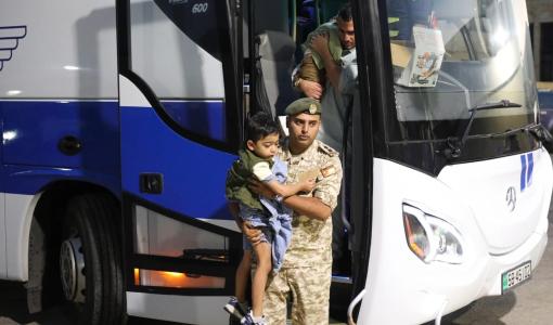 طفل من غزة يحمله أحد أفراد القوات المسلحة خلال رحلة العودة إلى قطاع غزة 26/8/2026