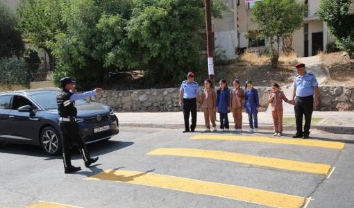 رجال أمن عام ينظمون حركة المرور لمساعدة مجموعة من طلاب المدارس على عبور الشارع