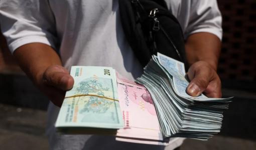 شخص يحمل أوراقا من الريال الإيراني في البازار الكبير بطهران 17/8/2026 | رويترز
