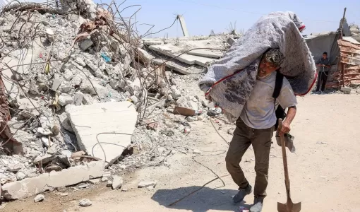 فلسطيني يسير بجانب الأنقاض في مخيم للنازحين بغزة | وكالة الأنباء الفرنسية