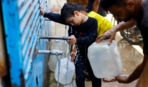 فلسطينيون يملؤون عبوات المياه في نقطة توزيع مياه بالنصيرات وسط قطاع غزة | رويترز