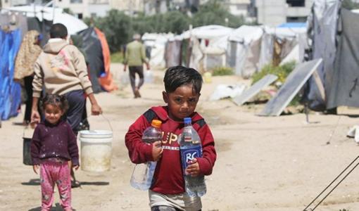 طفل ينقل المياه بعبوات في مخيم البريج | القدس العربي