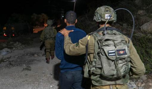 جندي من جيش الاحتلال يقتاد فلسطينيا لاعتقاله