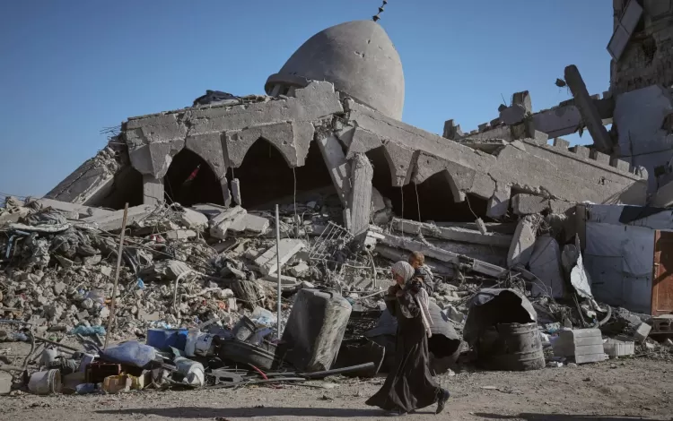 فلسطينية تحمل طفلها وهي تسير أمام مسجد مدمر بمدينة غزة فلسطينية تحمل طفلها وهي تسير أمام مسجد مدمر بمدينة غزة 26/10/2025 | أسوشييتد برس