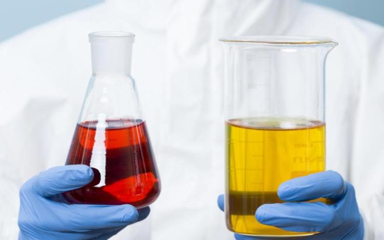 اختصاصي كيمياء يحمل زجاجتين لمواد كيميائية | تعبيرية Freepik