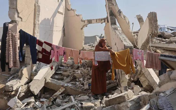 سيدة فلسطينية تقف وسط أنقاض منزل مدمر في غزة تنشر ملابس على حبل غسيل يمتد بين الركام 18/11/2025 | وكالة الأنباء الفرنسية