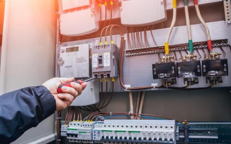 فني كهرباء يستخدم مفكا أثناء العمل داخل لوحة كهربائية | تعبيرية