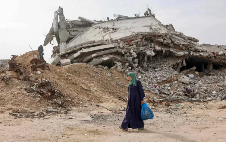 فلسطينية نازحة تمر أمام مبنى مدمر في حي تل الهوى جنوب مدينة غزة 29/11/2025 | وكالة الأنباء الفرنسية