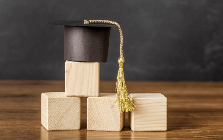 قبعة تخرج فوق مكعبات خشبية | تعبيرية freepik