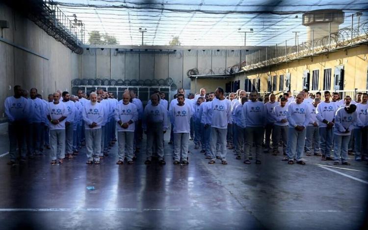 أسرى فلسطينيون داخل أحد سجون الاحتلال الإسرائيلي يرتدون قمصانا كتب عليها "لا ننسى ولا نغفر"