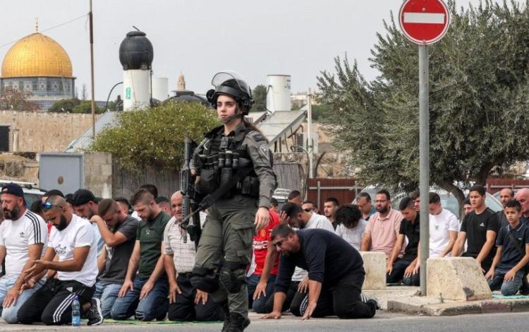 مجندة من جيش الاحتلال تمر بجانب المصلين أثناء صلاة الجمعة | أرشيفية