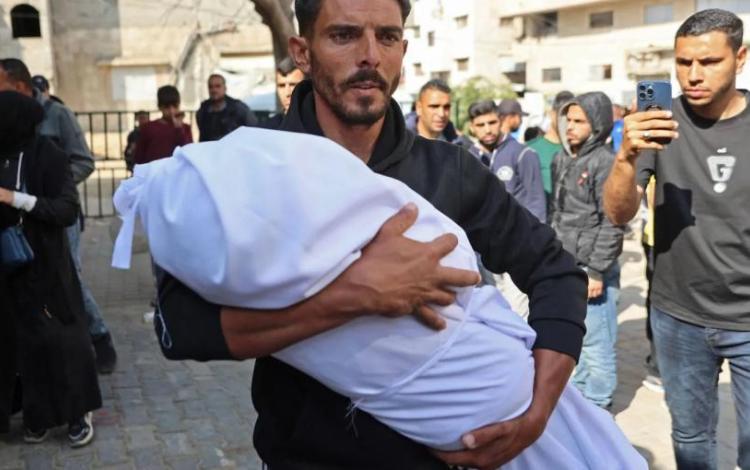 رجل يحمل جثمان طفل استشهد جراء قصف مدفعي إسرائيلي على منازل سكنية قرب مستشفى كمال عدوان في بيت لاهيا شمال قطاع غزة 25/4/2026 | وكالة الأنباء الفرنسية