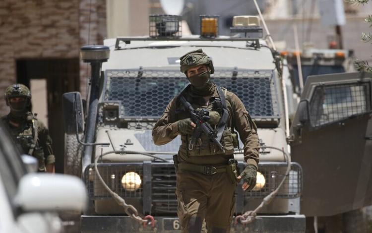 أحد جنود الاحتلال يقف بالقرب من مدرعة عسكرية في الضفة الغربية | الأناضول