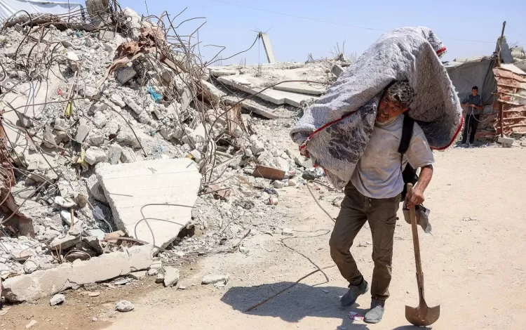 فلسطيني يسير بجانب الأنقاض في مخيم للنازحين بغزة | وكالة الأنباء الفرنسية
