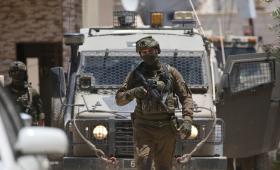 أحد جنود الاحتلال يقف بالقرب من مدرعة عسكرية في الضفة الغربية | الأناضول