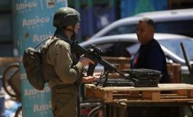 جندي من جيش الاحتلال يعيق تحرك فلسطيني في إحدى بلدات الضفة الغربية | الأناضول
